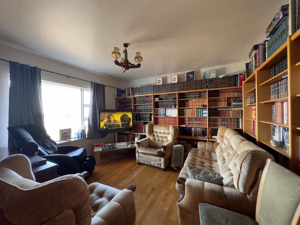 a living room with two couches and bookshelves at Fagrabrekka Private Room in Staður