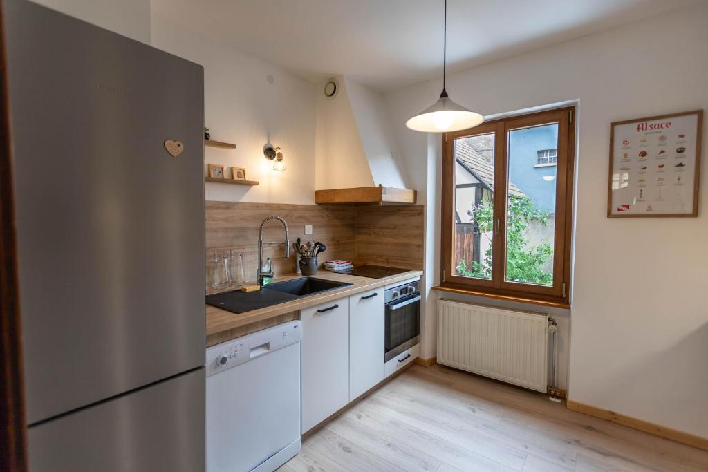uma cozinha com um frigorífico de aço inoxidável e um lavatório em Aux Cerfs des Vignes - Groupe em Scherwiller