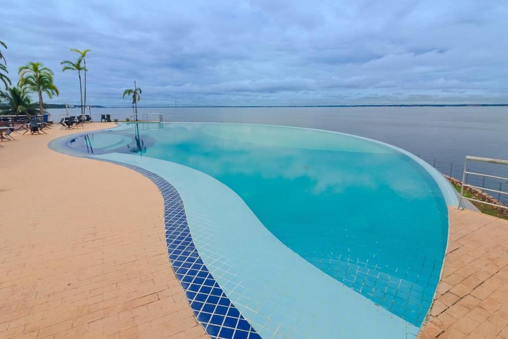 uma grande piscina azul ao lado de um corpo de água em Tropical Executive N 905 em Manaus