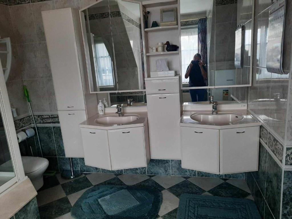 a woman taking a picture of a bathroom with two sinks at Logies in Knokke-Heist