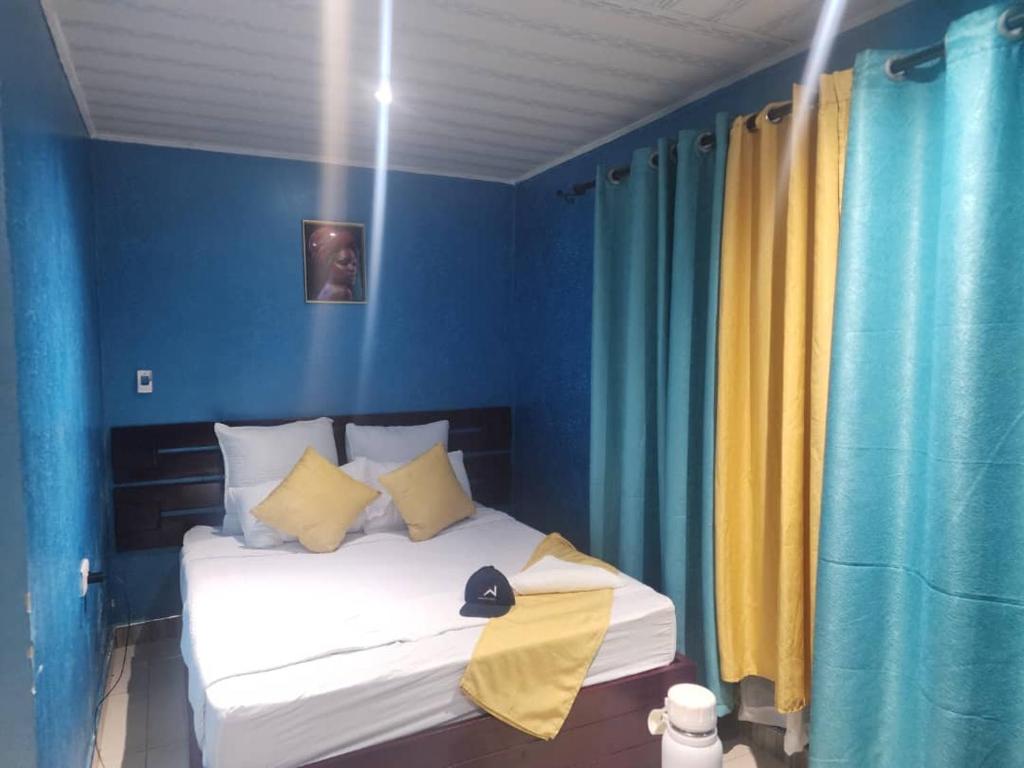 a bedroom with a bed with blue walls and yellow curtains at Bukari Executive Lodge in Mpongwe