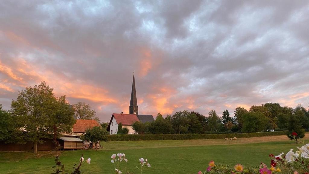 una iglesia con campanario y animales en un campo en Ferienwohnung am Chursbach en Callenberg