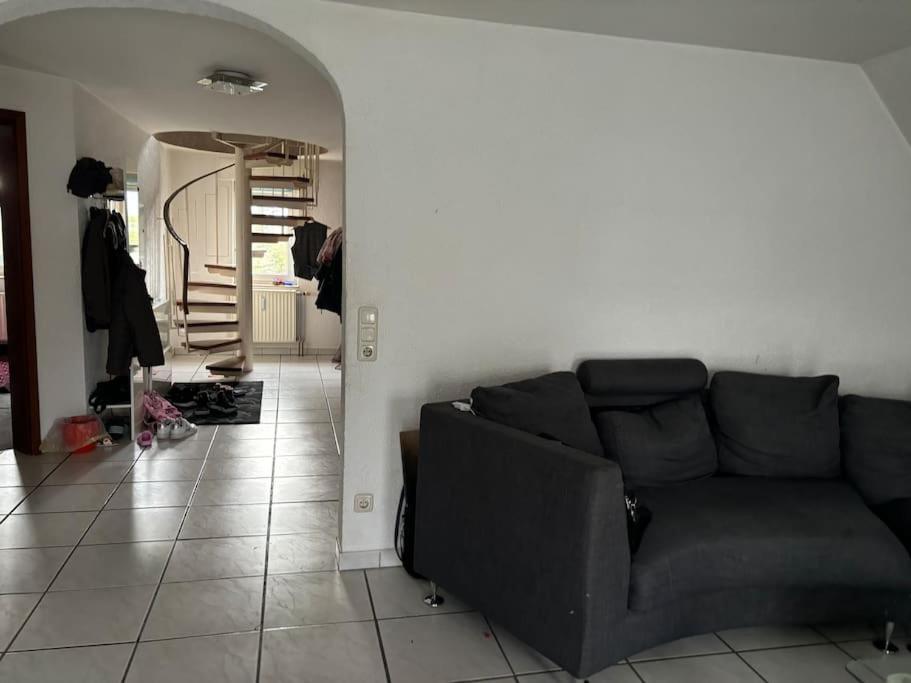 un salon avec un canapé noir et un couloir dans l'établissement Maisonette Wohnung in Bergheim:, à Bergheim