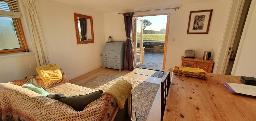 a living room with a couch and a wooden floor at Apple Tree Barn - converted barn with meadow views in Helston