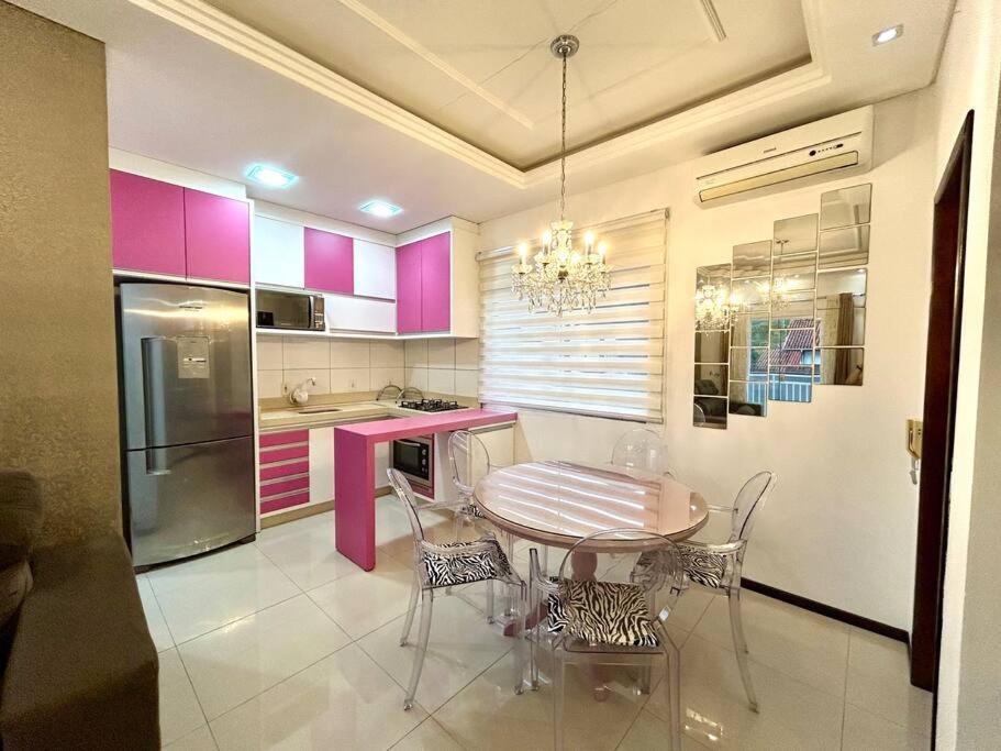 cocina con mesa, sillas y armarios rosados en Apartamento inteiro muito aconchegante en Joinville