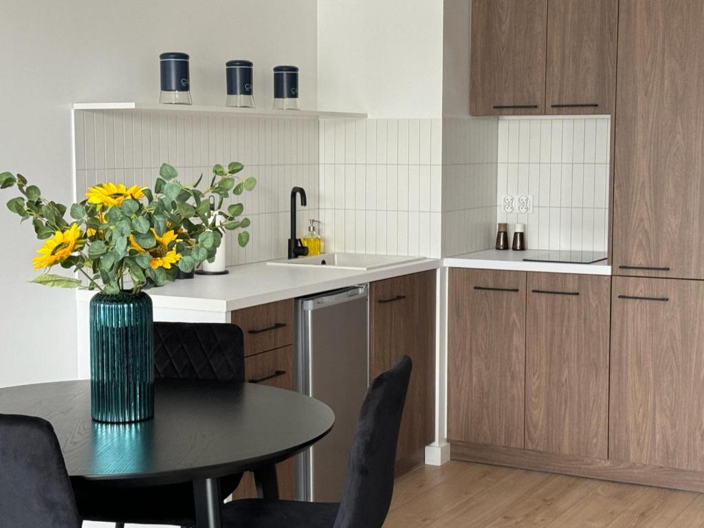 a kitchen with a table and a vase with yellow flowers at Apartament Przystań 2 in Kartuzy