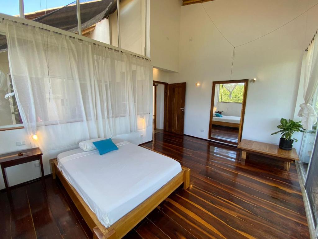 a bedroom with a white bed and a wooden floor at Casa Cosmonova in Puerto López