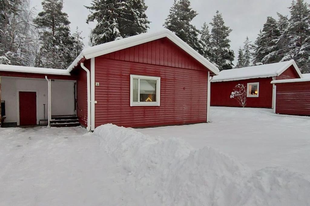 a red house with a pile of snow in front of it at Vindelälv Stuga in Blattnicksele in Blattniksele