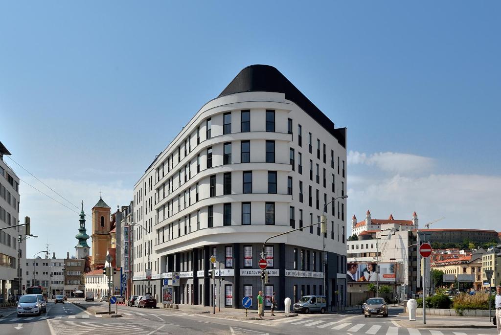 ein großes weißes Gebäude mit einem schwarzen Dach auf einer Stadtstraße in der Unterkunft Charming & Cozy Ambiente Apartments in Bratislava