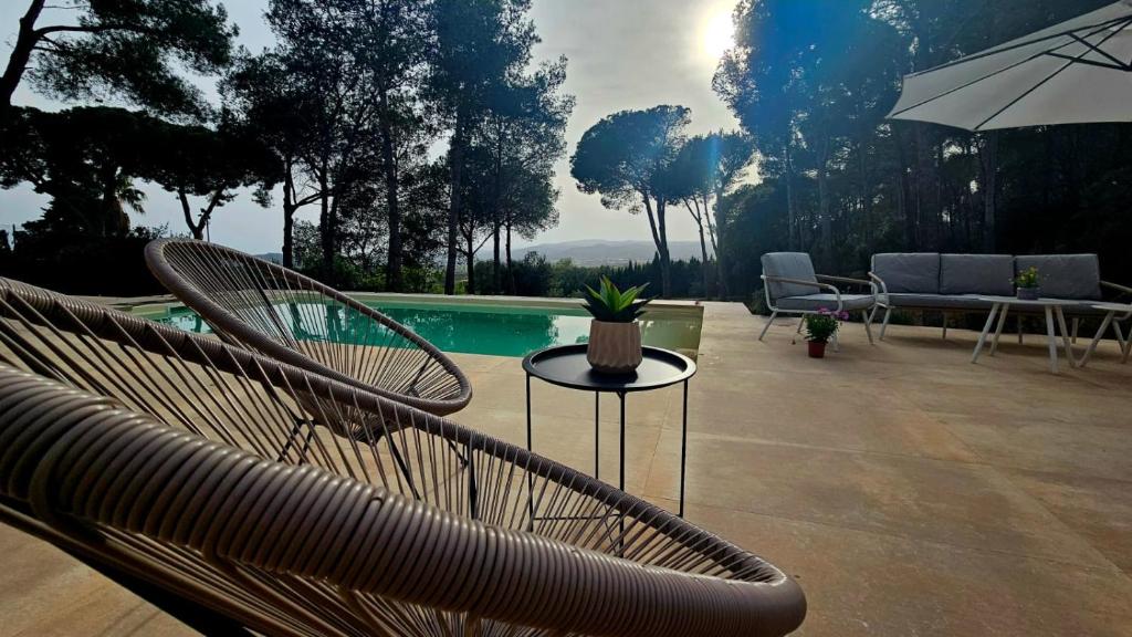 a patio with chairs and an umbrella and a pool at La vinya in Palafrugell