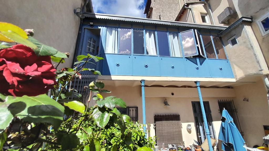 - un balcon sur une maison avec une fleur rouge dans l'établissement Appart charme Arenes Nimes, à Nîmes