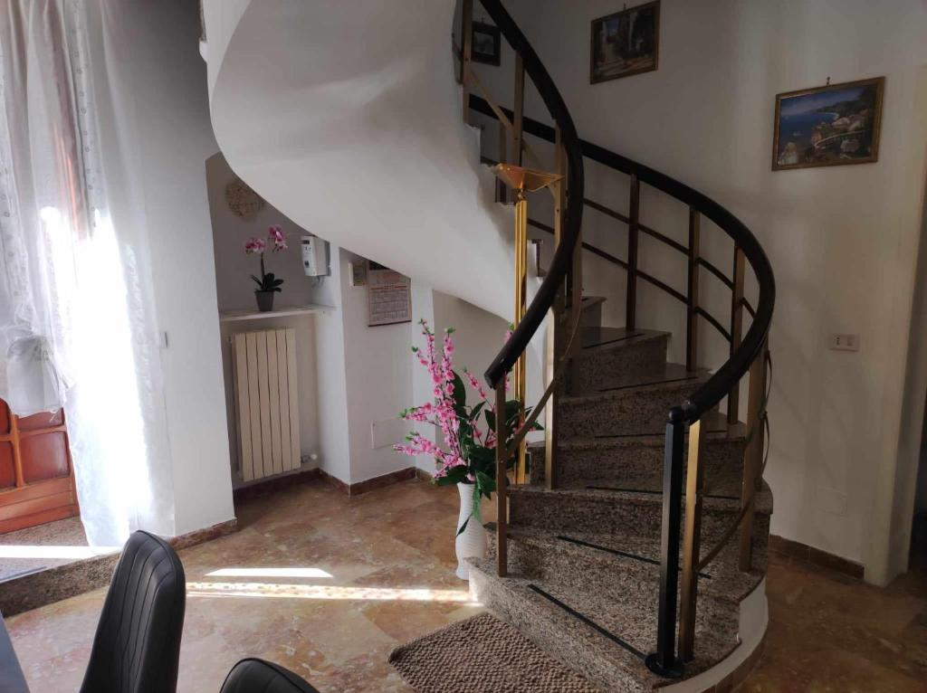 una scala a chiocciola in una casa con vaso di fiori di Appartamento Cuore Salento a Carmiano