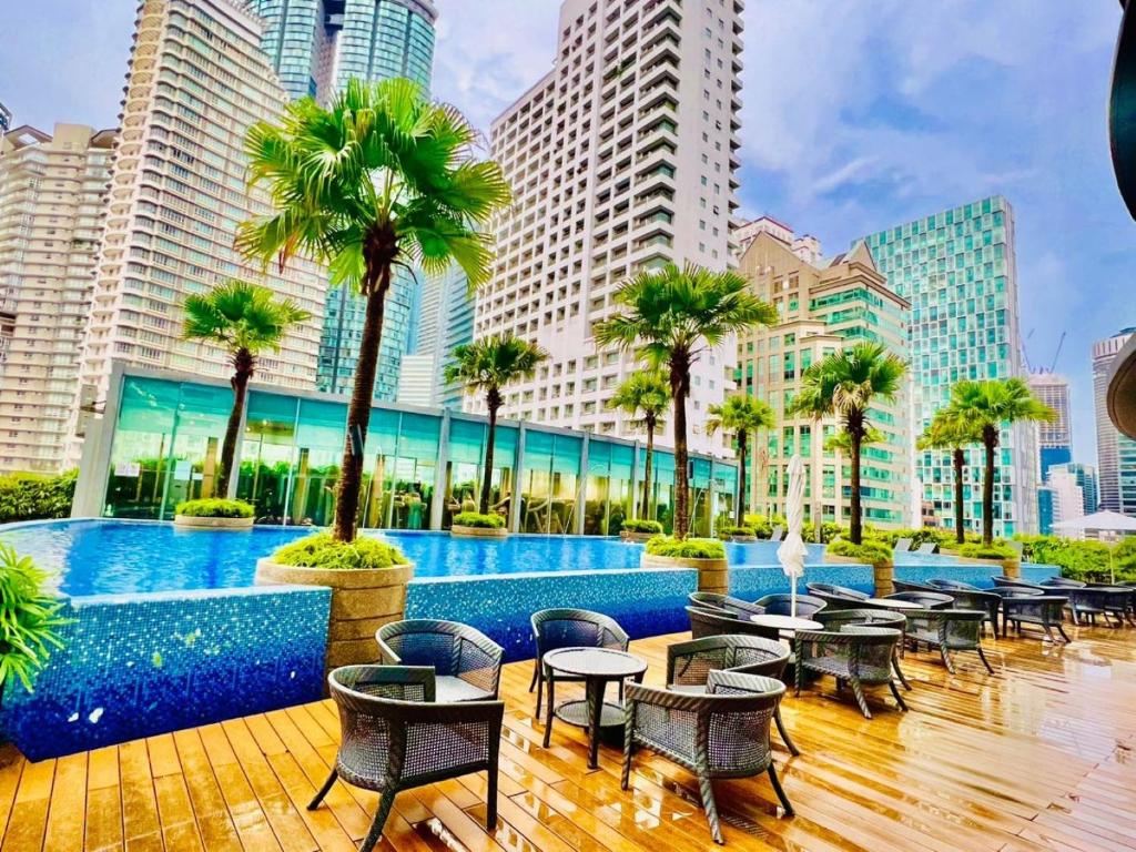 a hotel patio with tables and chairs and palm trees at VORTEX KLCC Apartment Kuala Lumpur Bukit Bintang in Kuala Lumpur