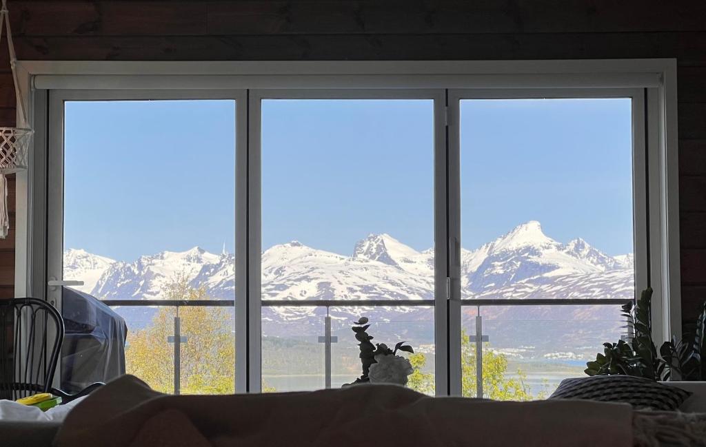 a view of snow covered mountains through a window at Exclusive view villa in Tromsø