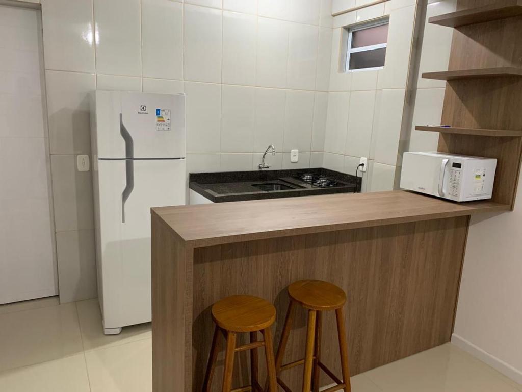 een keuken met een aanrecht met 2 krukken en een koelkast bij Pousada Thereza in Bento Gonçalves
