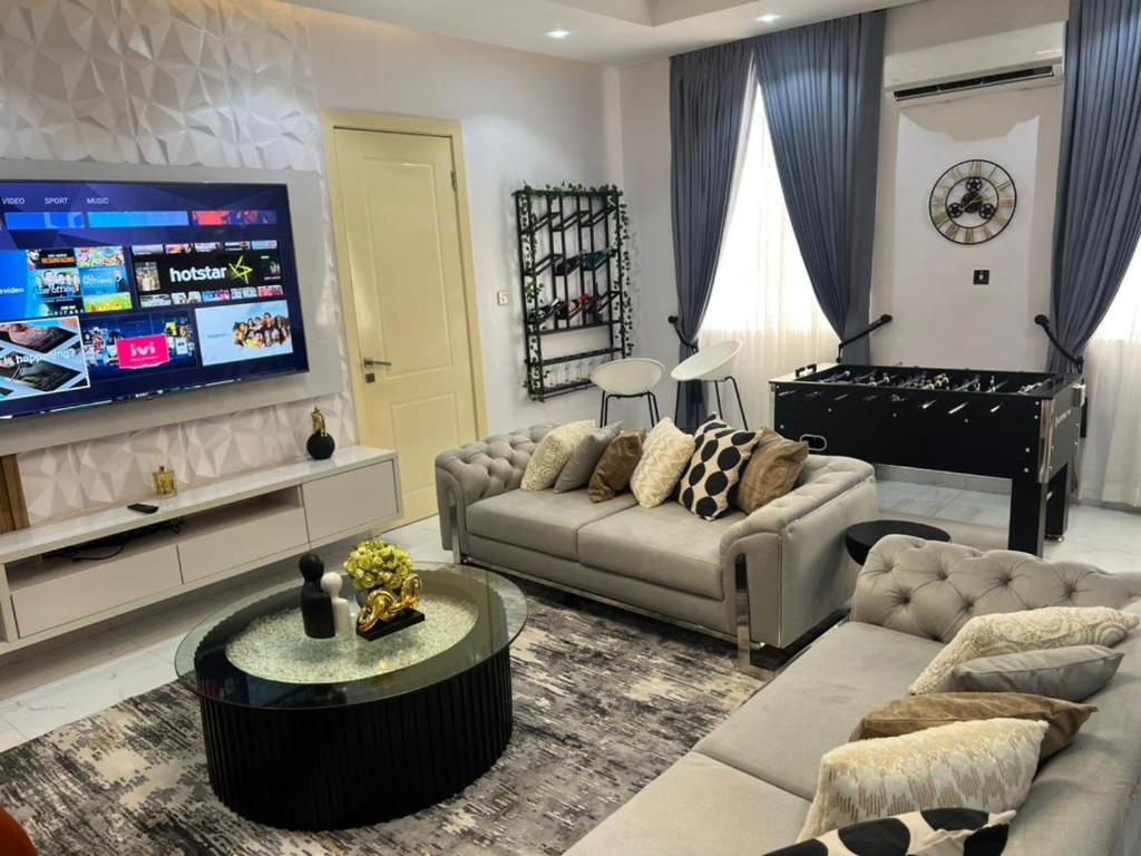 a living room with a couch and a tv and a piano at Rod Apartments in Lagos