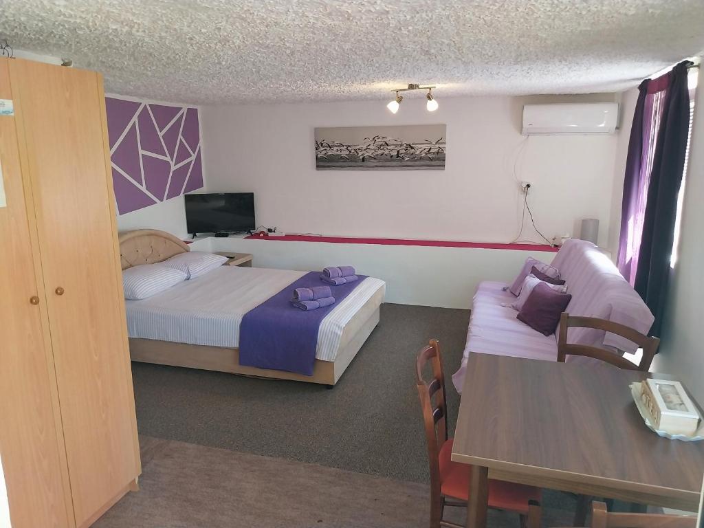 una camera d'albergo con due letti, un tavolo e una televisione di Petkovic Apartmani 2 a Tivat
