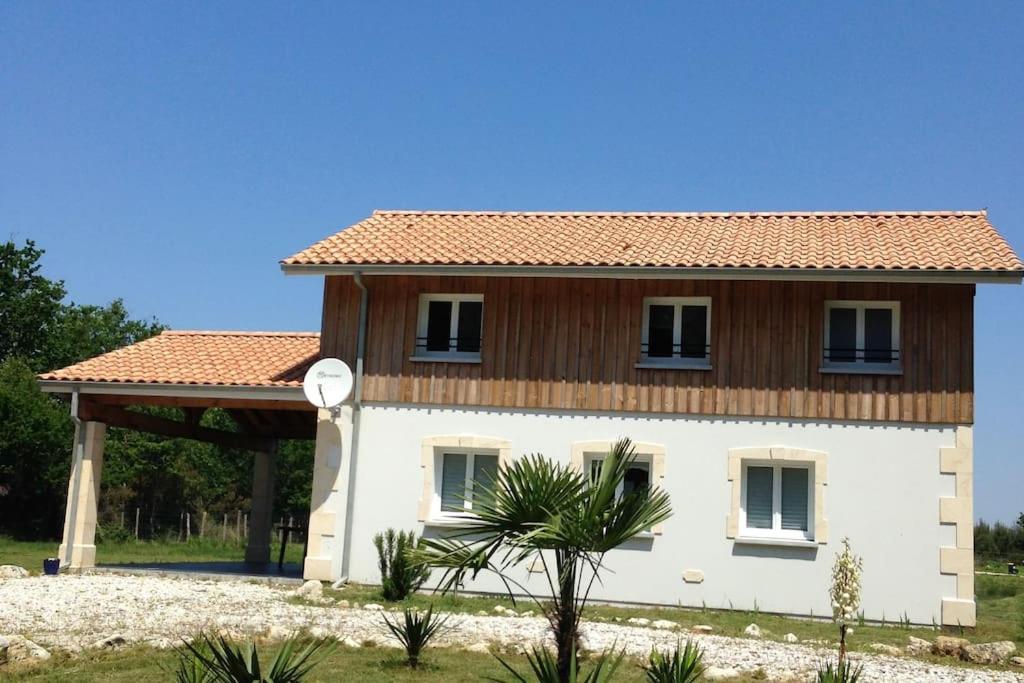 a white house with a wooden roof at Maison proche du lac ! in Hourtin