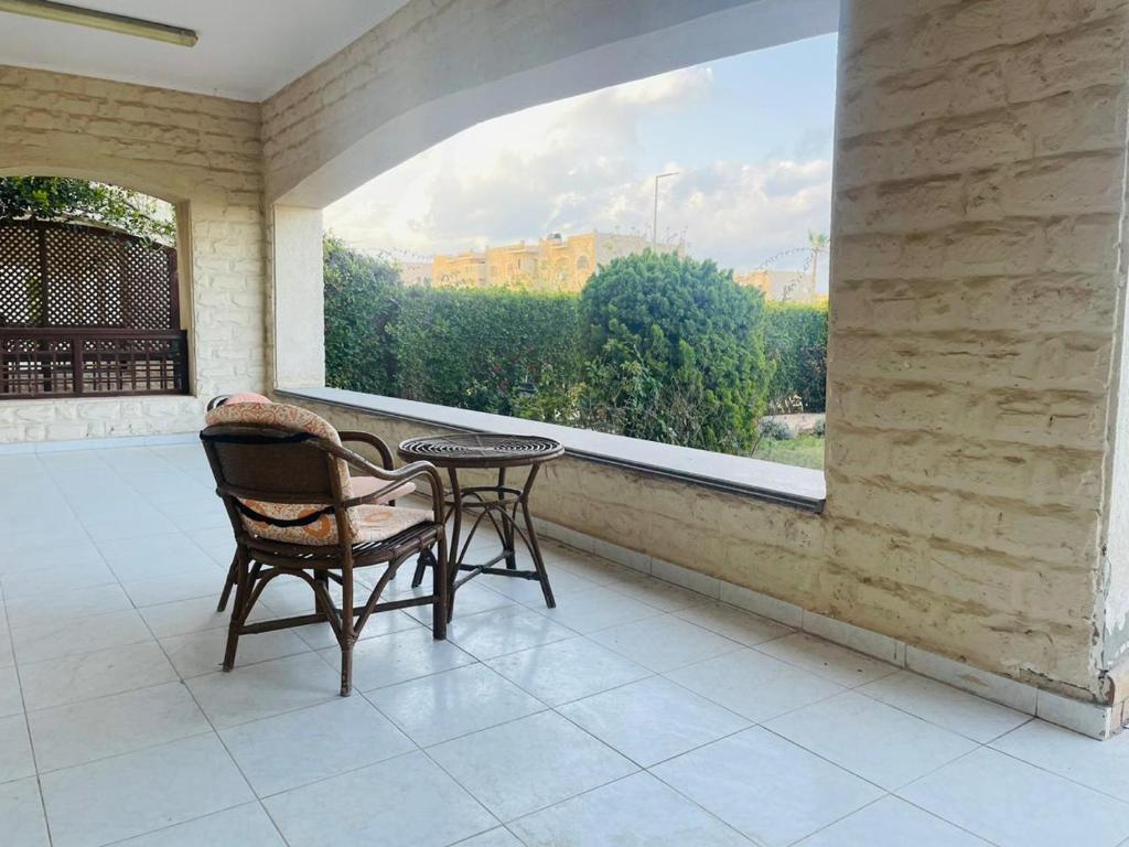 a balcony with two chairs and a table and a window at Hasna chalet in El Alamein