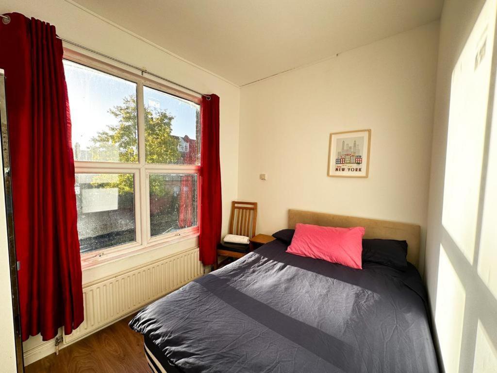 a bedroom with a bed and a window with red curtains at Mount nod rooms in London