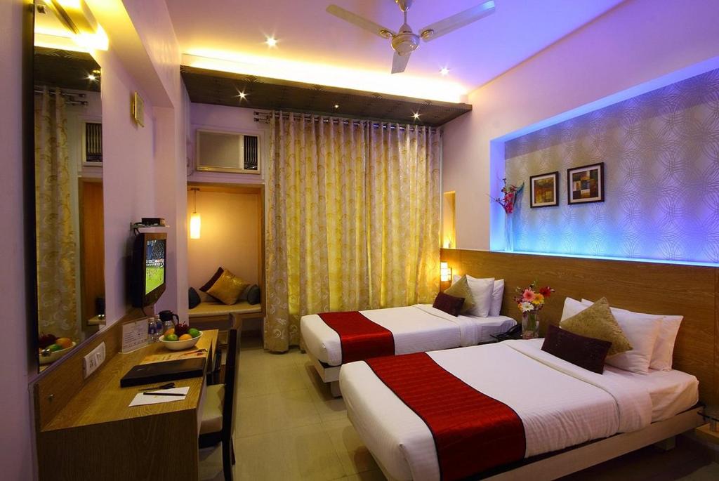 Habitación de hotel con 2 camas y escritorio en Vihang's Inn en Thane