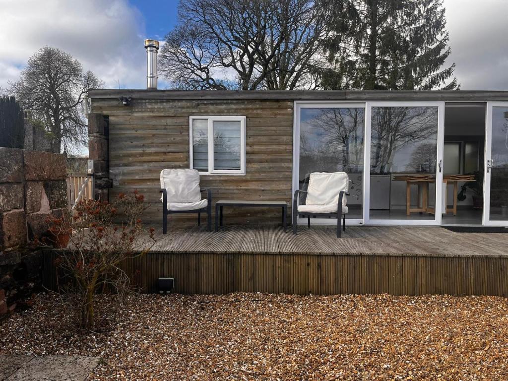 Country Cabin Retreat - Hideaway & Relax في ثورنهيل: منزل صغير مع كرسيين وطاولة على السطح