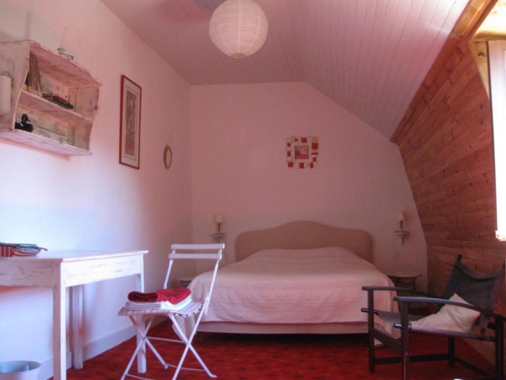 a bedroom with a bed and a desk and chairs at Chambres d'hôtes de charme Le Pradel in Monceaux-sur-Dordogne