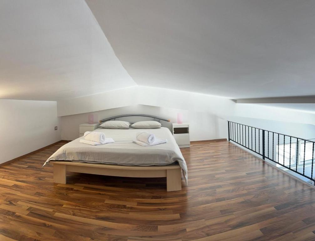 um quarto branco com uma cama e piso em madeira em Apartment Štucin em Vipava