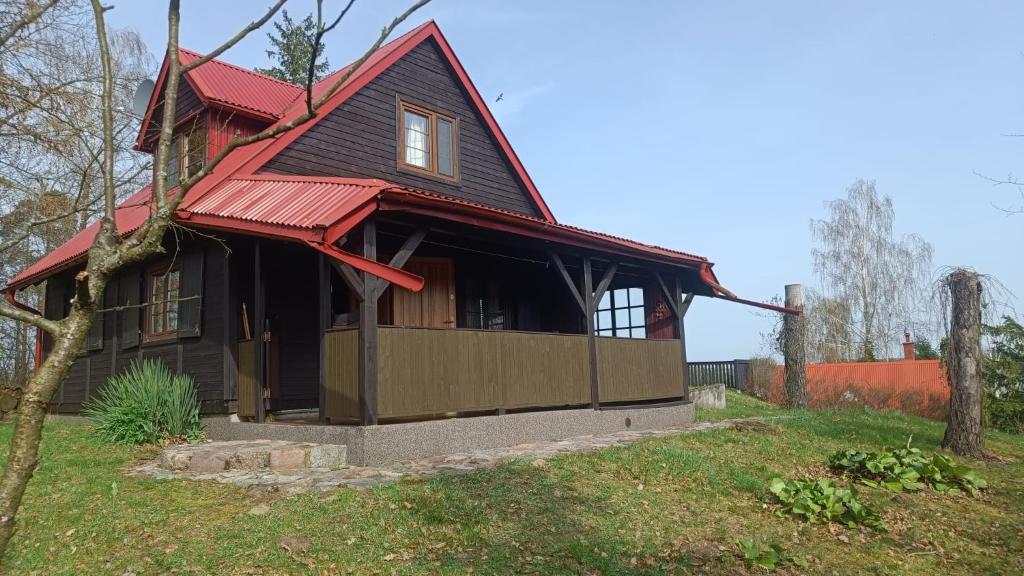 a house with a red roof on a yard at Domek wypoczynkowy Gowidlino in Gowidlino