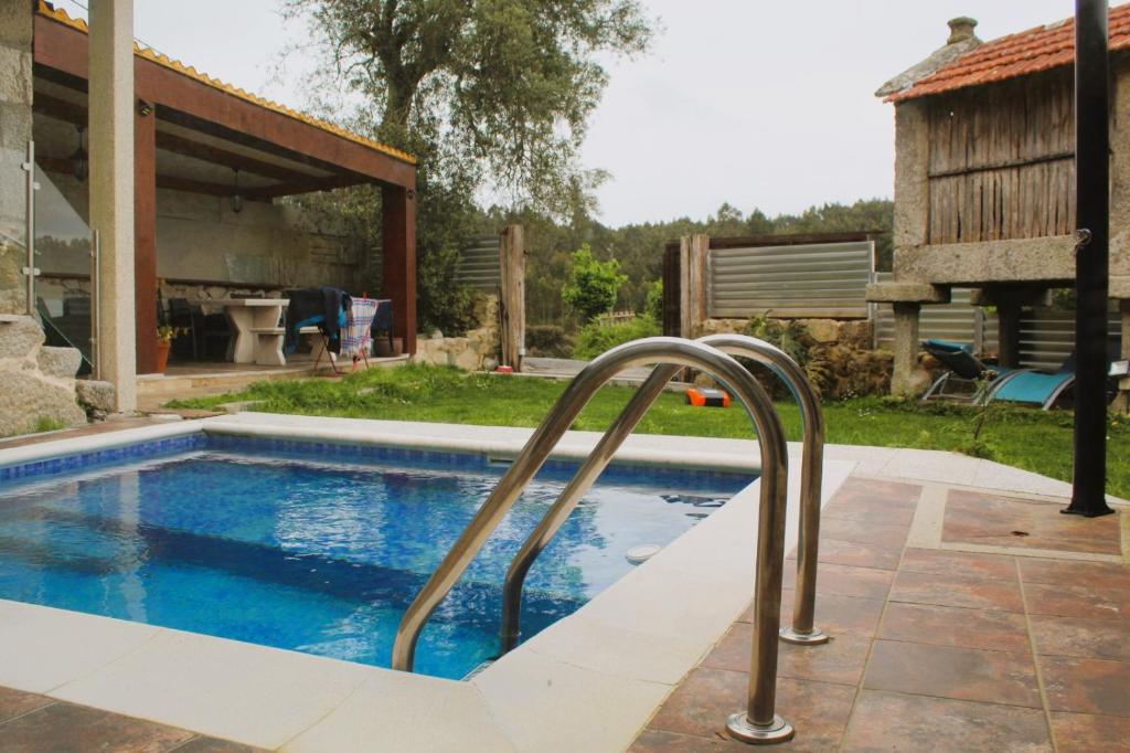 a swimming pool with a hand rail in a yard at Casa rustica en Armenteira in Pontevedra