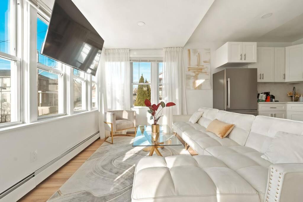 a white living room with a white couch and some windows at Stunning Luxury 3BR Entire Home in NY with Easy Parking! in Yonkers