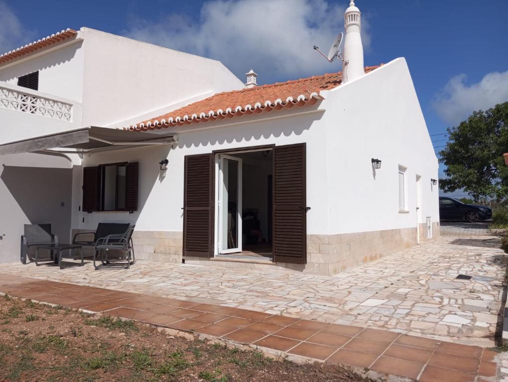 a white house with a porch and chairs at Casa Raios de Sol in Burgau