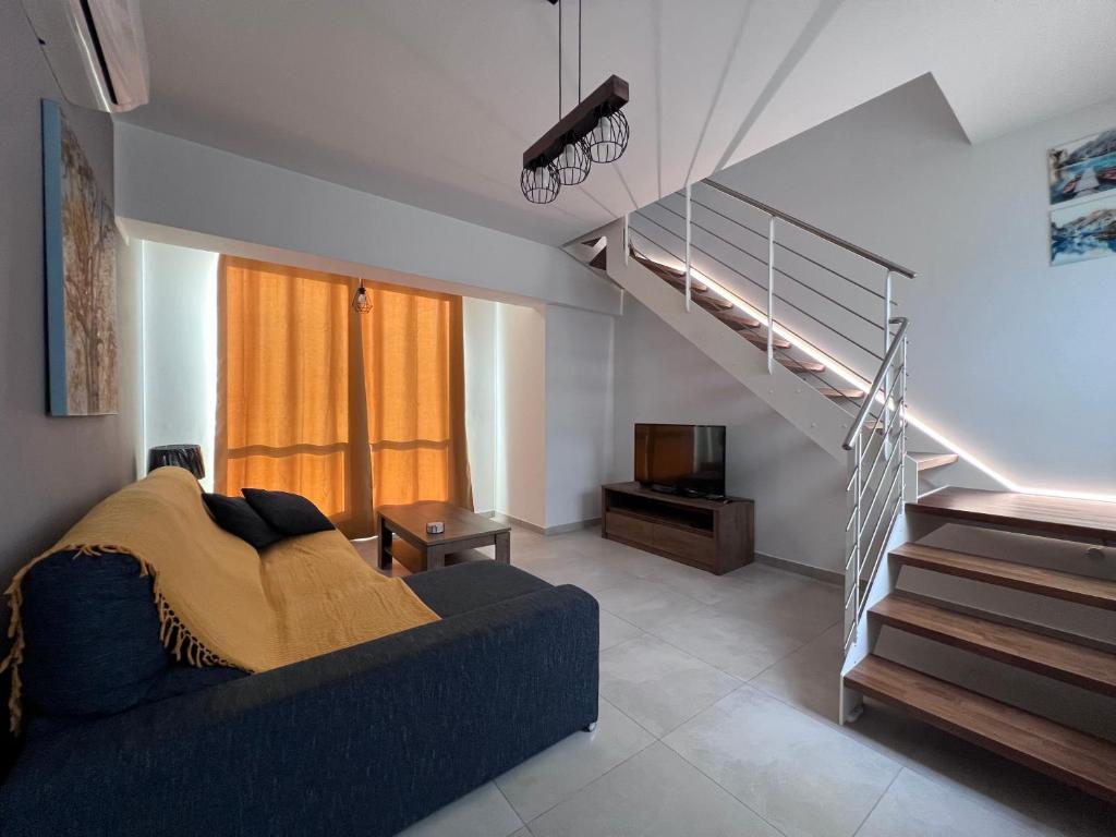 a living room with a blue couch and a staircase at Zenia Court in Marsaskala