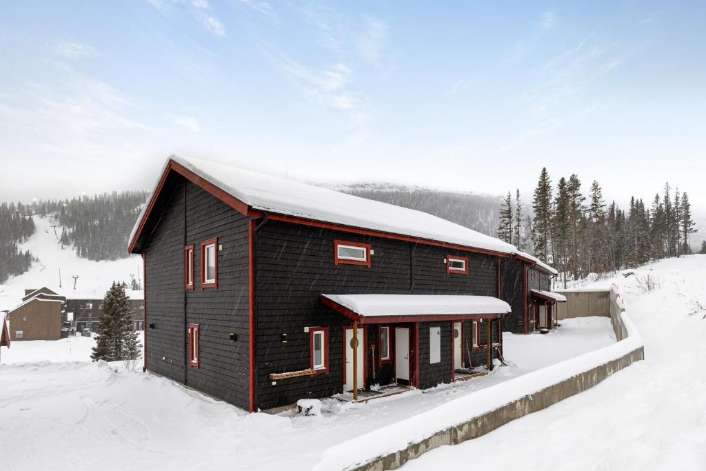 una cabaña negra con nieve en el techo en Parkstigens Lägenheter, en Funäsdalen