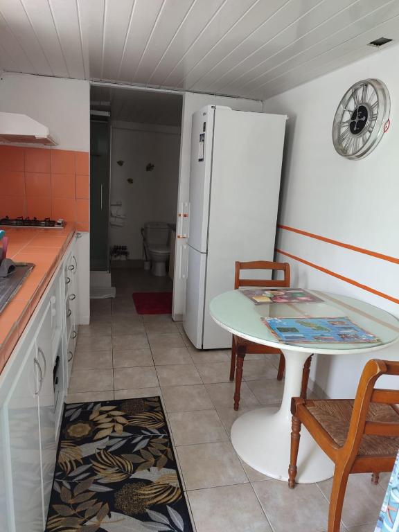 een keuken met een tafel en een witte koelkast bij La maison du bonheur in Fort-de-France