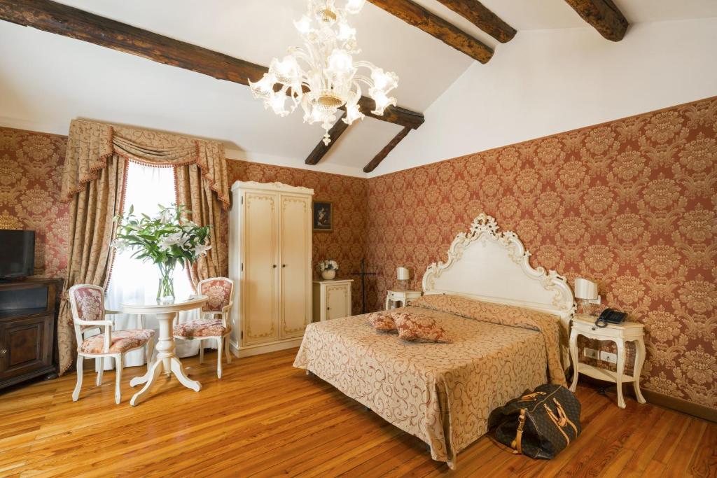 a hotel room with a bed, chair, table and lamps at Palazzo Guardi in Venice