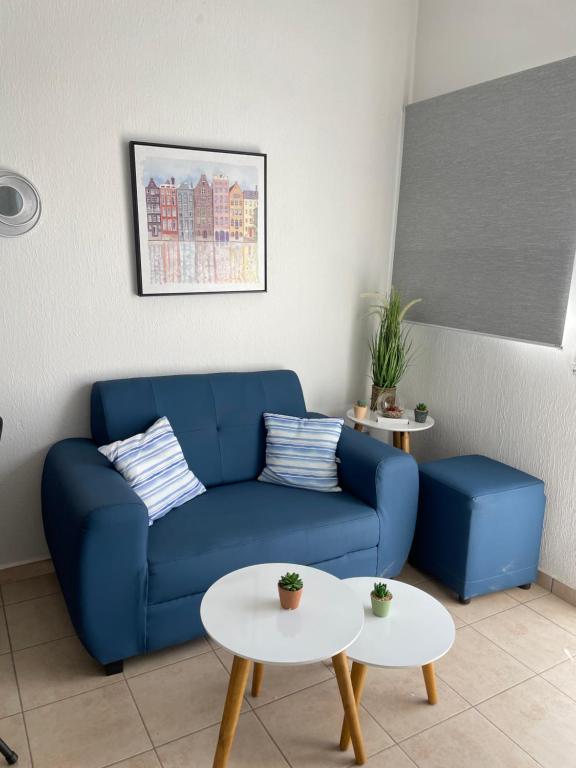 sala de estar con sofá azul y 2 mesas en Tiny house Santa Ana en Santa Ana