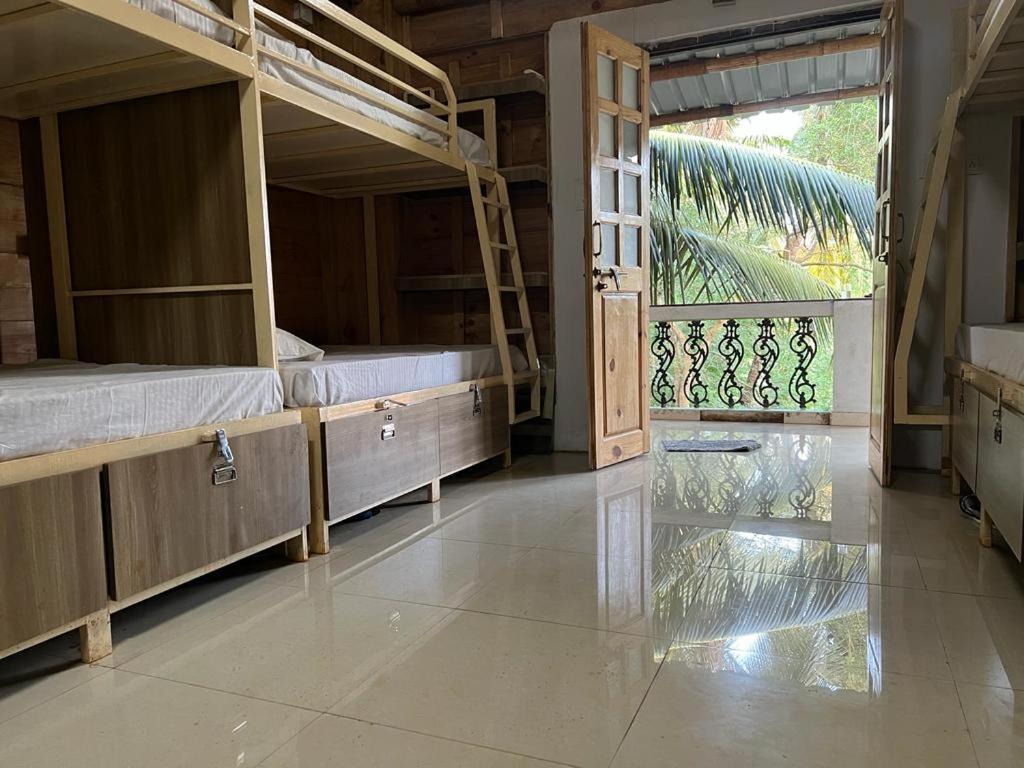 a room with two bunk beds and a large window at Jeet Hostel & Rooms in Canacona