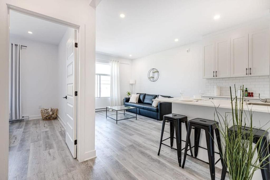 a white kitchen and living room with a blue couch at M11 Neat & Spacious 1BR in Heart of Plateau MTL in Montréal