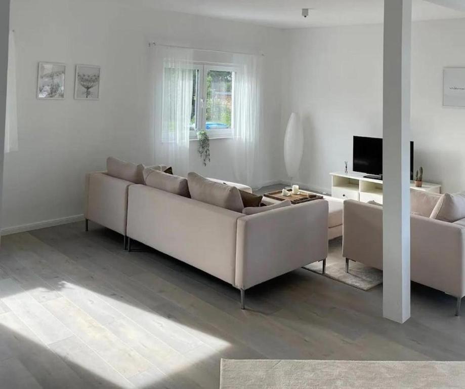 Sala de estar con 2 sofás blancos y TV en HOME OF VACATION - Landhausstil zum Wohlfühlen - FREE WIFI & NETFLIX, en Adelheidsdorf