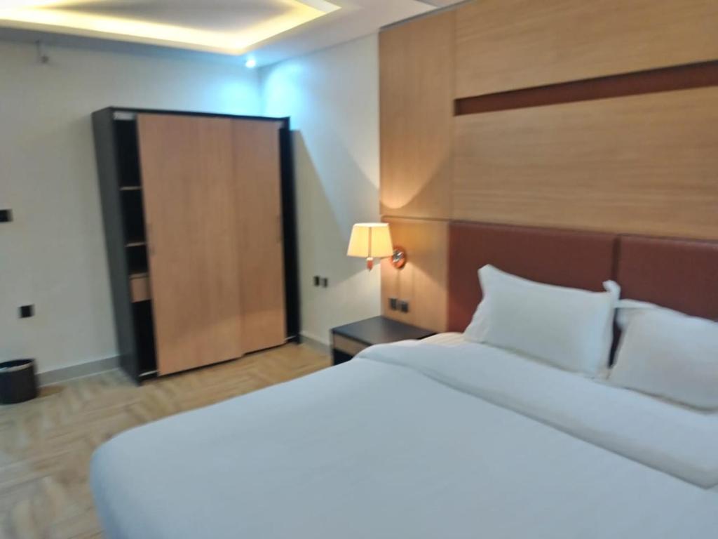 1 dormitorio con 1 cama blanca grande y cabecero de madera en Jeddah Grand Beach, en Yeda