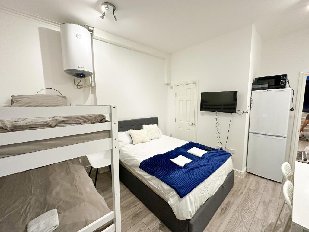a bedroom with two bunk beds and a refrigerator at Chapel studios in Ilford