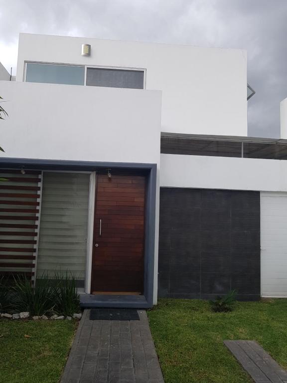 una casa blanca con una puerta marrón en un patio en Bonita casa al norte de Aguascalientes en Jesús María