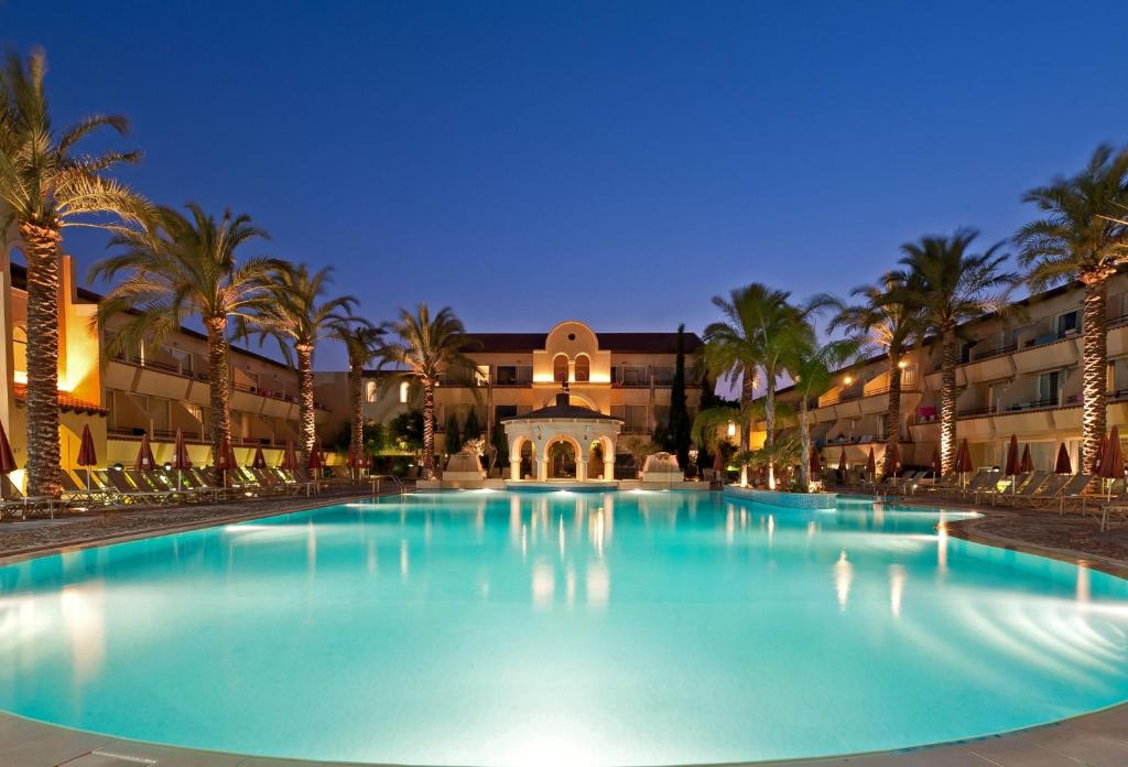 a large pool with palm trees in front of a building at Napa Plaza Hotel (Adults Only) in Ayia Napa