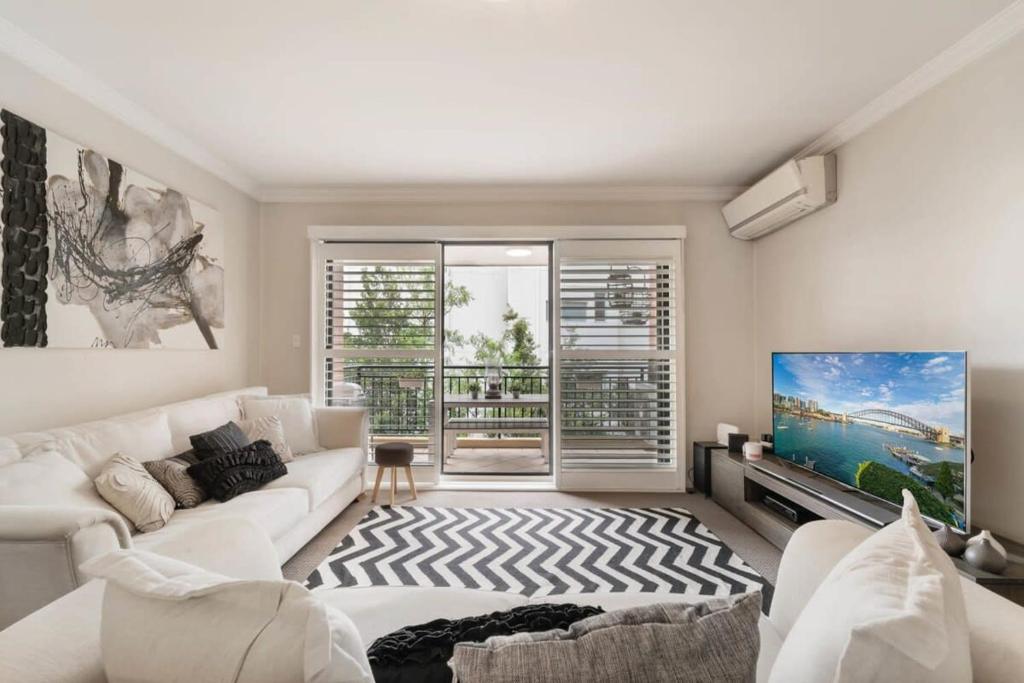 雪梨的住宿－Walk to Coogee Beach Apartment Retreat，客厅配有白色沙发和平面电视。