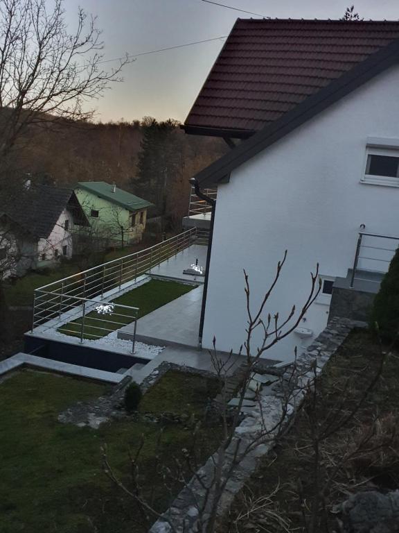 um edifício branco com um deque e um quintal em Kuća za odmor na Mrežnici em Duga Resa
