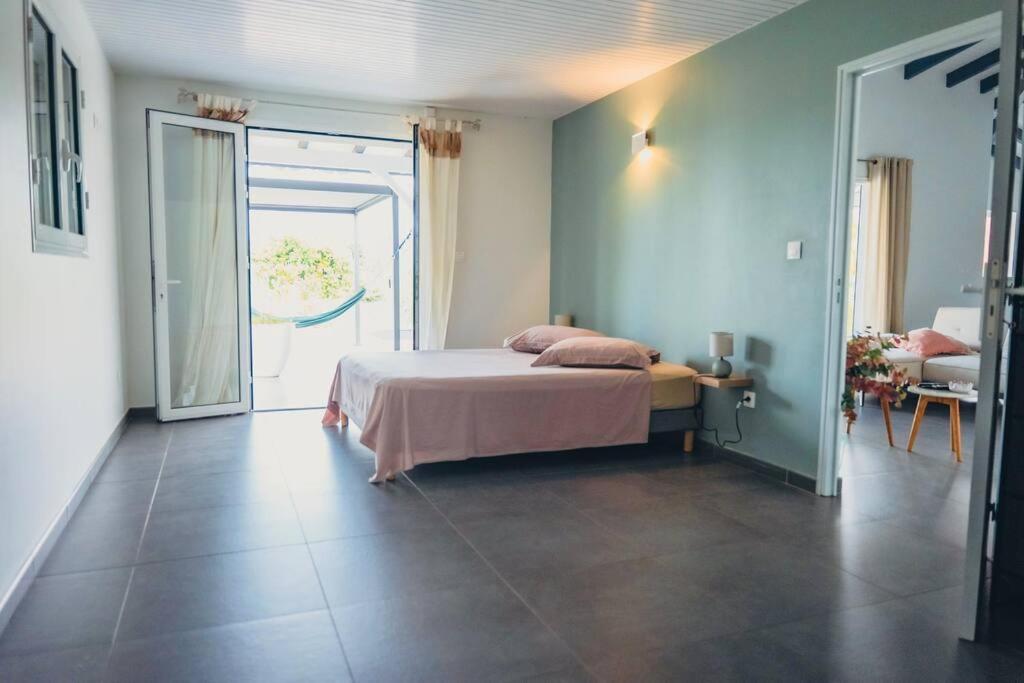 1 dormitorio con 1 cama y puerta abierta en Villa Mahé, Majestueuse villa avec piscine, F4 à Ducos, en Ducos