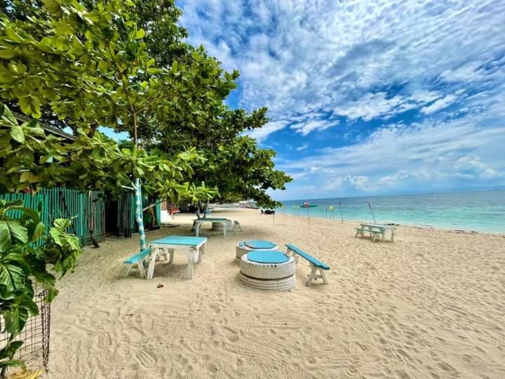 a beach with picnic tables and benches on the sand at Camotes Island Beachfront Vacation House in San Francisco