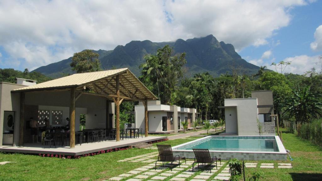 a resort with a swimming pool and mountains in the background at Vila do Porto Pousada in Morretes