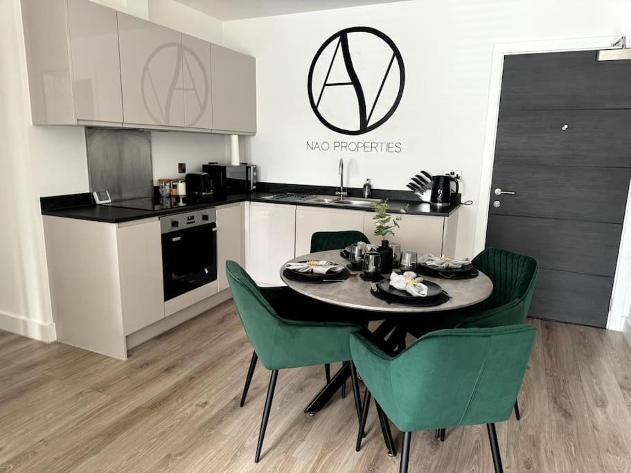 a kitchen with a table and green chairs in a room at Luxury Oaks Suite, Free private parking, 2 Bed 2 Bathroom Apartment, Central location in Birmingham